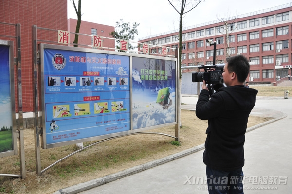 合肥市新聞中心工作人員正在拍攝安徽新華電腦專修學(xué)院消防安全欄
